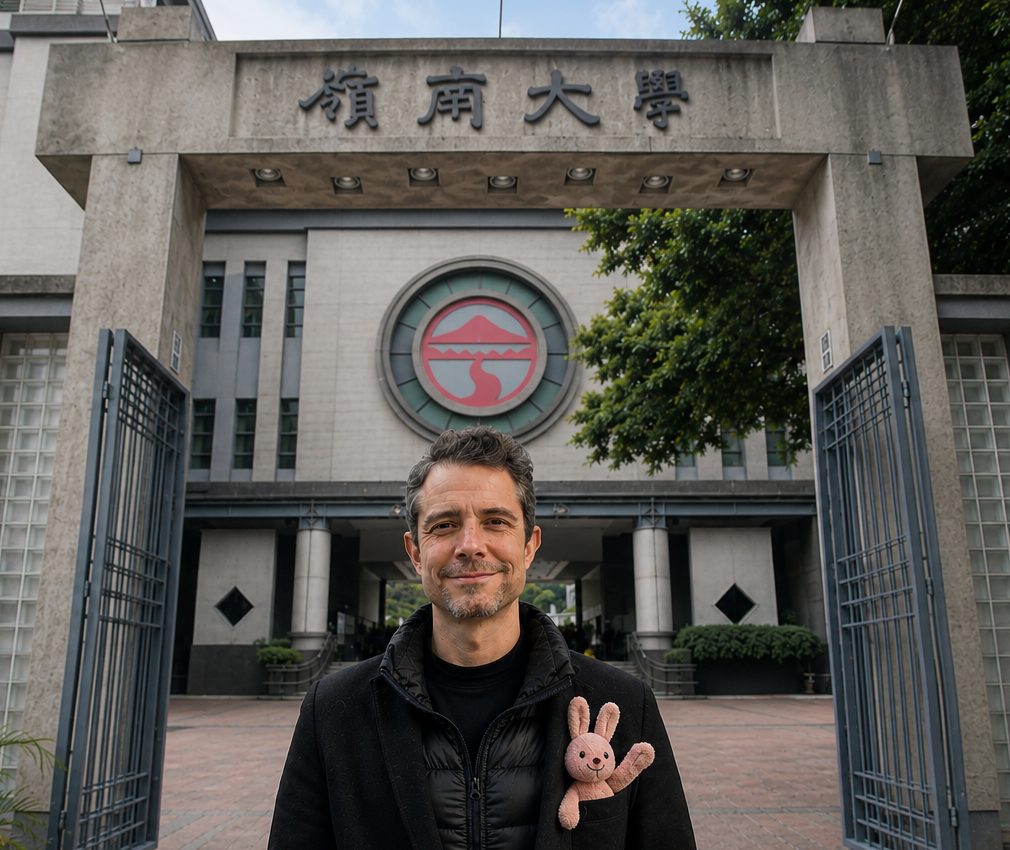 Darryl Sterk standing in the open gate of Lingnan University, a small pink toy rabbit waving from his coat pocket.